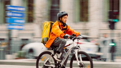Trabajar en Glovo: repartidor en bicicleta con la mochila de Glovo