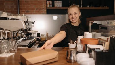 Empleada entregando un pedido en el mostrador de un pequeño negocio de comida