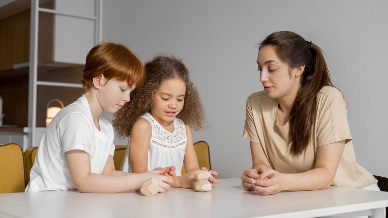 Au pair jugando con dos niños en la mesa de casa