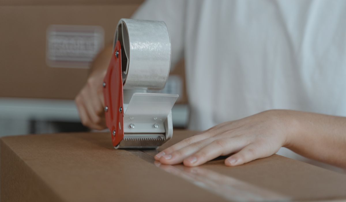 Trabajo desde casa empacando: cerrando una caja con cinta